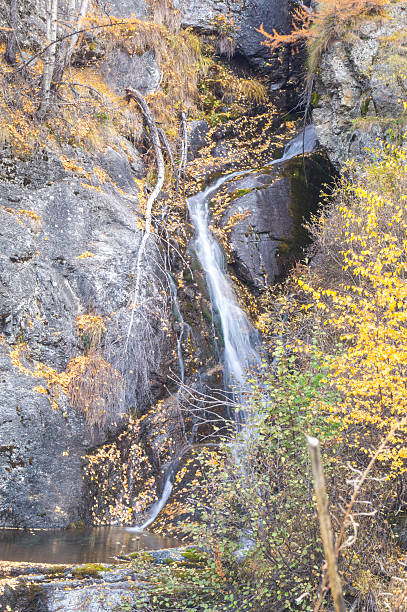 istock waterfall in the mountains and the autumnal trees, long exposure 619732484