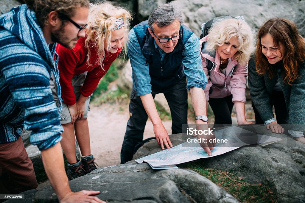 Group of Hikers checking route on map Group of Hikers checking route on map in the mountains Guide - Occupation Stock Photo