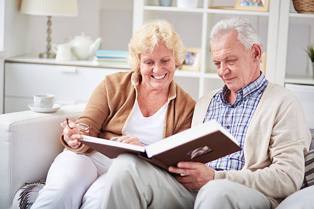 istock Senior couple sitting on sofa and looking through 619735414