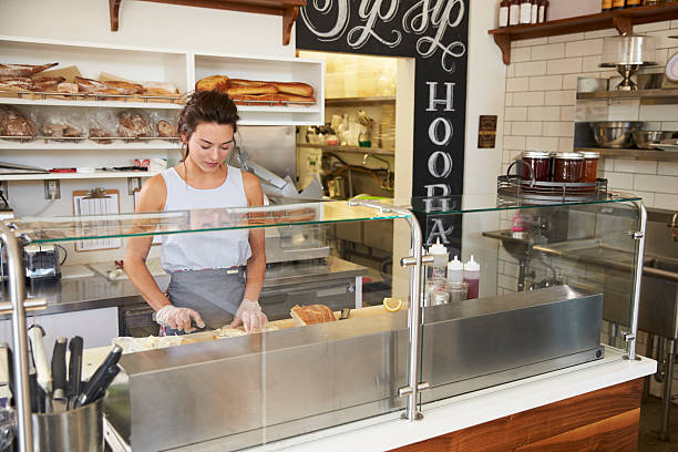 mujer trabajando detrás del mostrador en un bar de sándwiches - delicatessen small business cafeteria bar counter fotografías e imágenes de stock