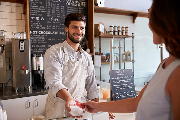 barista tomando el pago con tarjeta de un cliente en una cafetería - delicatessen small business cafeteria bar counter fotografías e imágenes de stock