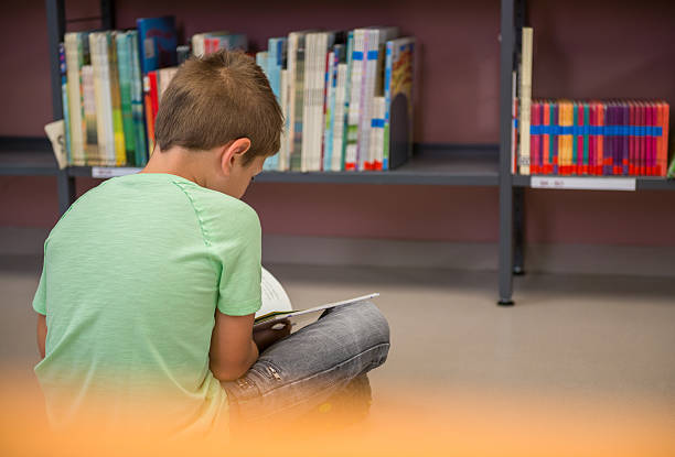 istock Schoolboy Sitting On The Floor In Library 619738458