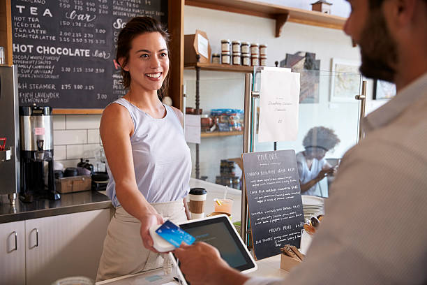 istock Customer at coffee shop pays smiling waitress with card 619738814
