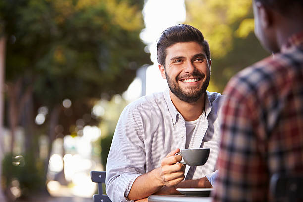 dwóch dorosłych mężczyzn przyjaciele siedzą rozmawiając przy kawie poza kawiarnią - selective focus coffee coffee crop cafe zdjęcia i obrazy z banku zdjęć