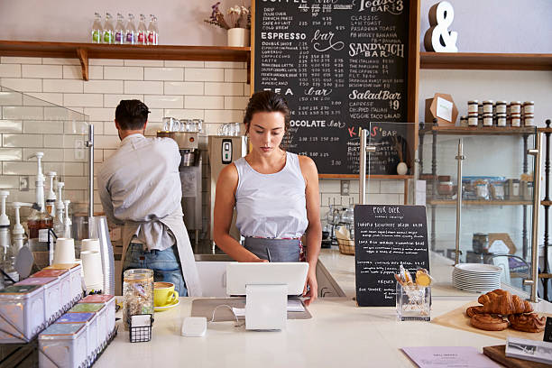 Couple working behind the counter at a coffee shop Couple working behind the counter at a coffee shop cash register photos stock pictures, royalty-free photos & images