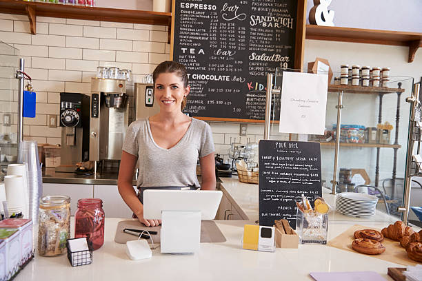 mujer esperando detrás del mostrador en una cafetería, - delicatessen small business cafeteria bar counter fotografías e imágenes de stock