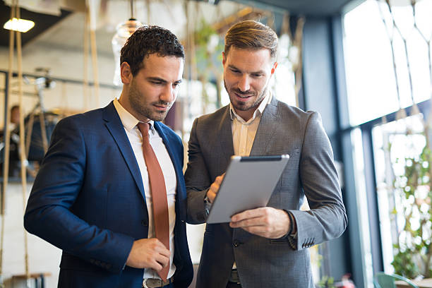 Two young businessmen discussing business strategy using digital tablet