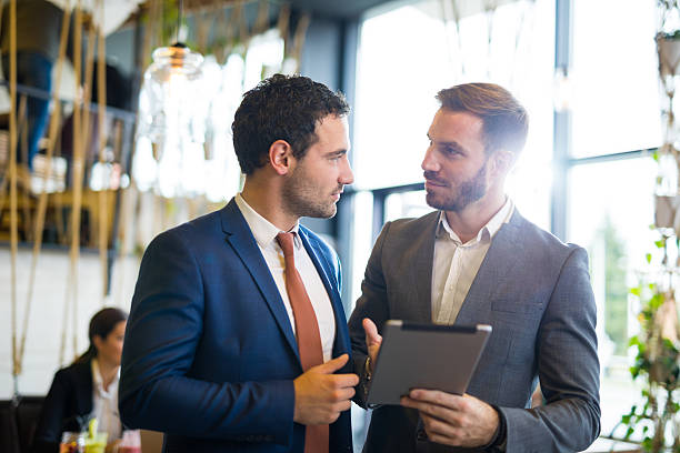 istock Two young businessmen discussing business strategy using digital tablet 619742880