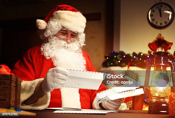 Santa Claus Sitting Near Christmas Tree And Reading Christmas Letter Stock Photo - Download Image Now