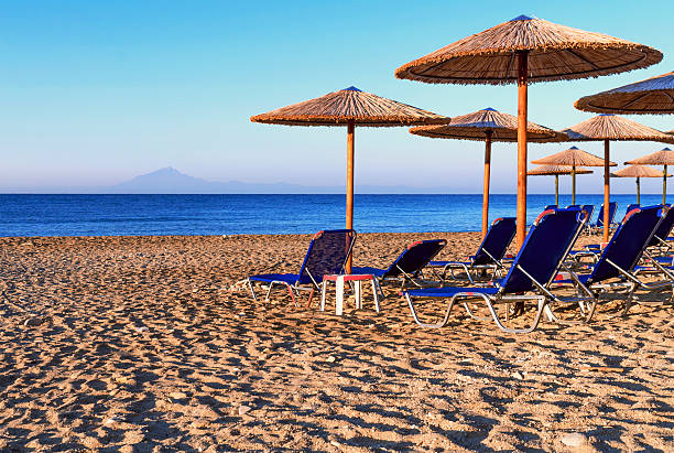 istock Sunbed, straw umbrella on beautiful rising sun beach background 619744230