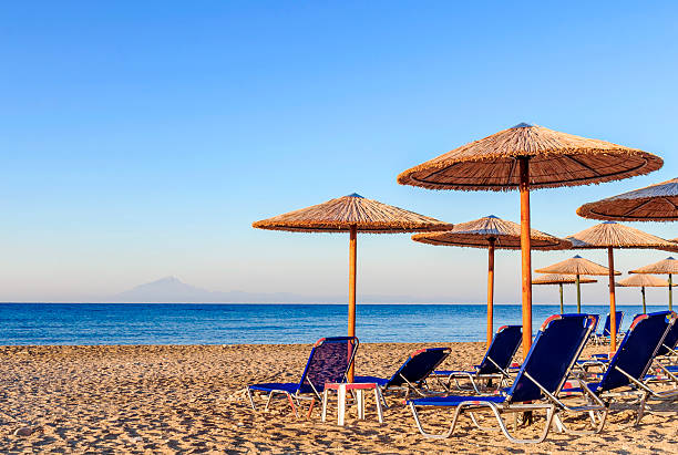 istock Sunbed, straw umbrella on beautiful rising sun beach background 619744494