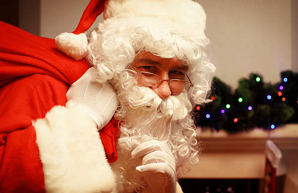 istock Santa Claus with huge sack keeping forefinger by his mouth 619745152