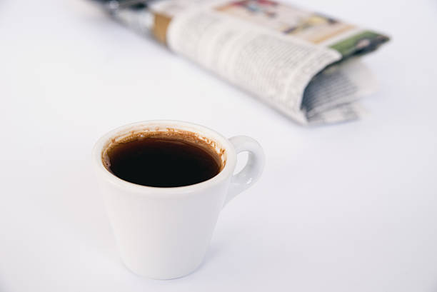 istock Newspaper with cup of coffee on white table 619745910
