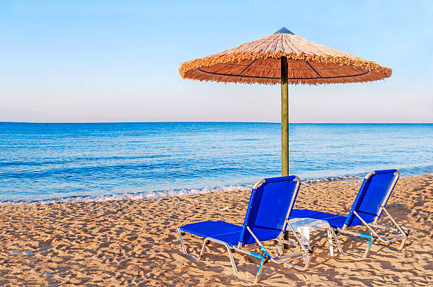 istock Two blue sunbed, straw umbrella on beautiful beach background 619746584