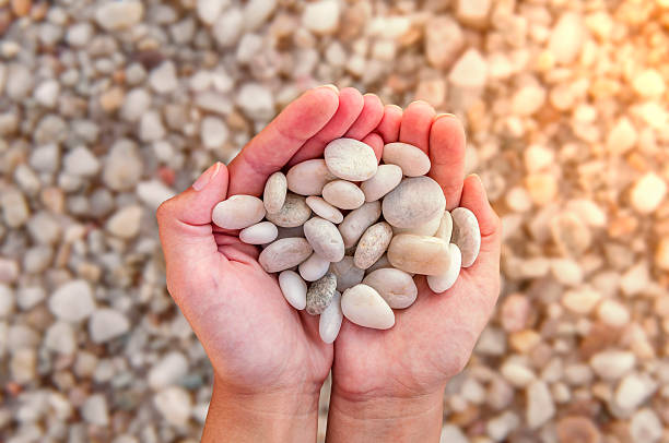 istock Woman hands holding small stones in hands on beach background 619748366