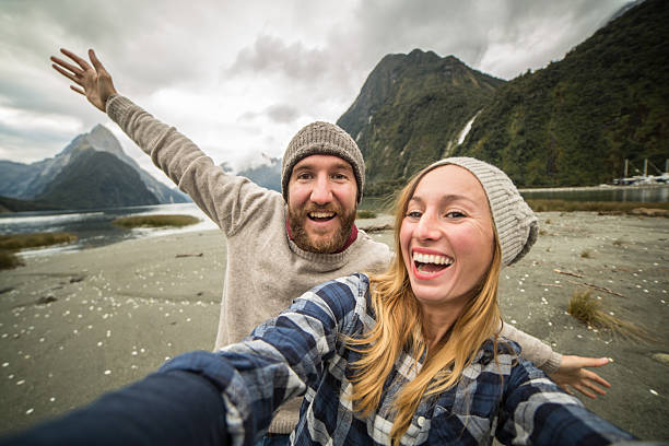 istock Two young adults traveling take selfie with mountain landscape 619748702