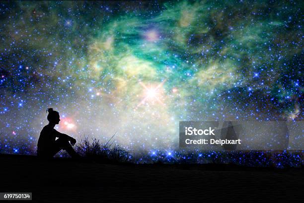 Silhouette Of A Woman Sitting Outside Starry Night Background Stock Photo - Download Image Now