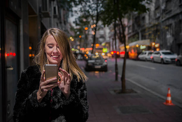 istock Happy beautiful woman walking and writing or reading sms messages 619751048
