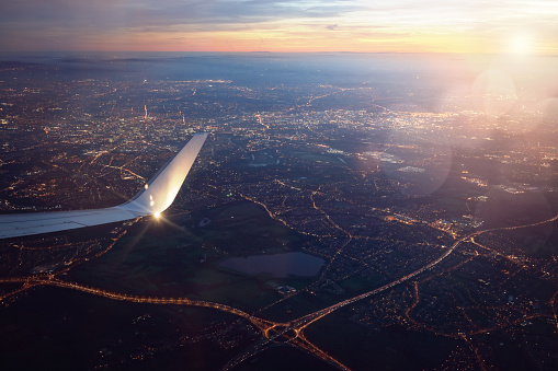 View from landing airplane window of city at sunset