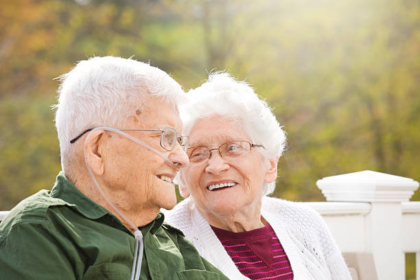 Happy Senior Couple Enjoying Conversation A happy 92 year old and his 89 year old wife enjoying eachother's company outdoors on a beautiful fall day. oxygen stock pictures, royalty-free photos & images