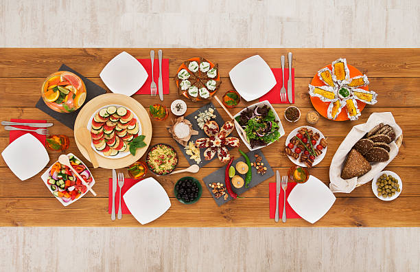 Healthy meals at festive table served for party. Authentic celebration with organic food on wooden table top view. Ratatoille, cheese, corn and chicken barbecue, sandwiches with mojito and lemonade