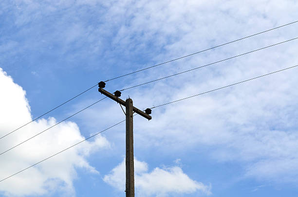 istock Electrical pole with power lines against hazy blue sky 619755430