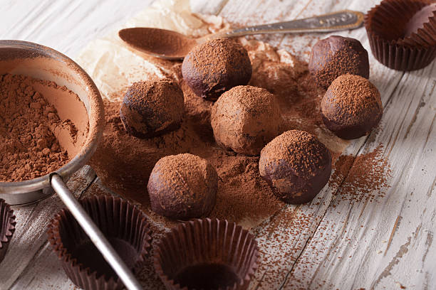 chocolate truffles sprinkled with cocoa powder close-up chocolate truffles sprinkled with cocoa powder close-up on the table. horizontal chocolate truffle making stock pictures, royalty-free photos & images