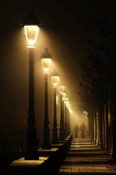 couple walking on dark street illuminated with streetlamps