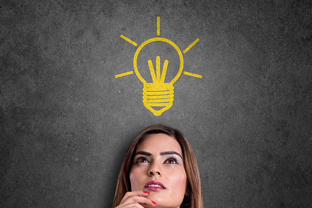 istock Businesswoman looking at glowing light bulb over her head 619757840