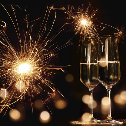 New Year motif at night with fireworks bokeh and two champagne glasses
