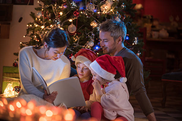 istock Christmas night. a nice family reading a book together 619760416