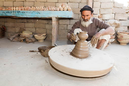 Jodhpur, India - December 4, 2015: Man forming a clay pot on the potter's wheel in Bishnoi village, Jodhpur, Rajasthan, India