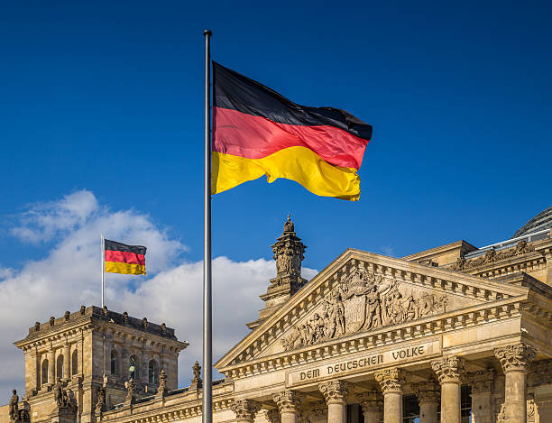 German flags at Reichstag, Berlin, Germany German flags waving in the wind at famous Reichstag building, seat of the German Parliament (Deutscher Bundestag), on a sunny day with blue sky and clouds, central Berlin Mitte district, Germany. bundestag stock pictures, royalty-free photos & images
