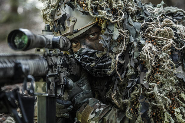 sniper wearing ghillie suit stock photo