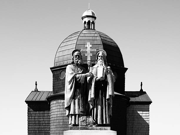 Religious statue and wooden chapel of Saint Cyril and Methodius on Radhost Mountain in Beskids, aka Beskydy, Czech Republic . Black and white image.
