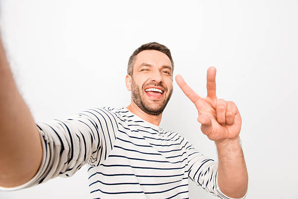 istock Happy cheerful laughing man making selfie and showing two finger 619771846