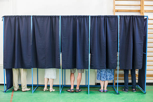 People voting in booths stock photo