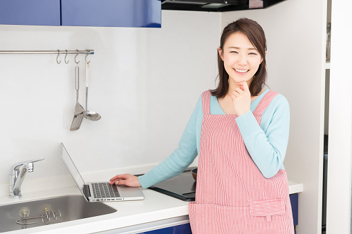 Japanese woman usign a PC in the kitchen