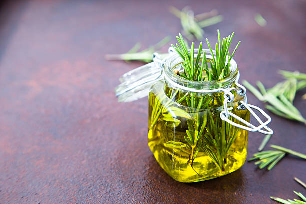 Rosemary oil. Rosemary essential oil jar glass bottle and branch Rosemary oil. Rosemary essential oil jar glass bottle and branches of plant rosemary with flowers on rustic background. rosemary stock pictures, royalty-free photos & images