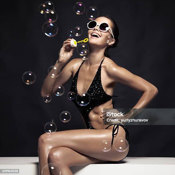 Beautiful Tan Female Model Posing In Bikini And Blow Bubbles Stock Photo - Download Image Now