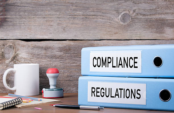 istock Compliance and Regulations. Two binders on desk 619965996