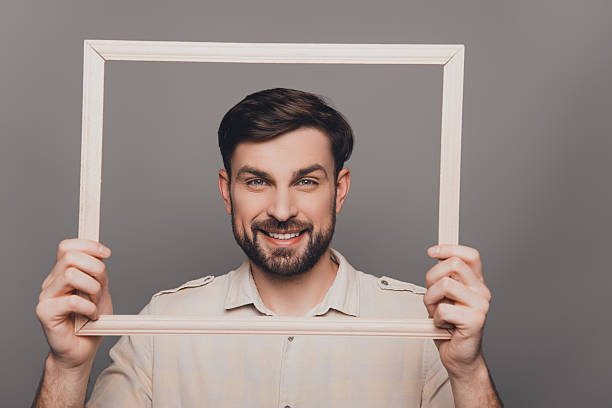 istock Handsome happy young guy holding wooden frame 619971852
