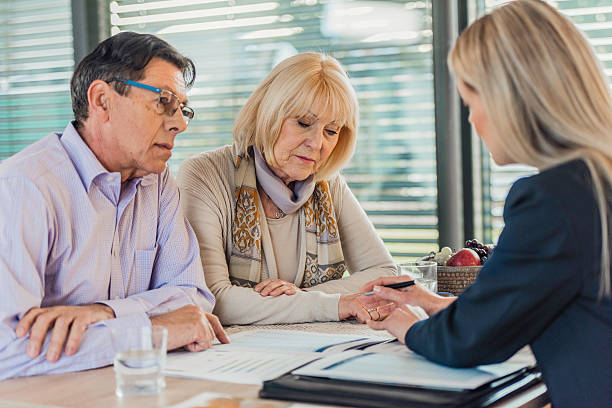 istock Insurance agent presenting contract to mature couple 619973910