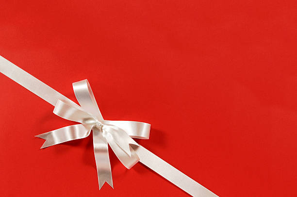 istock White gift bow ribbon red paper background corner diagonal 619977690