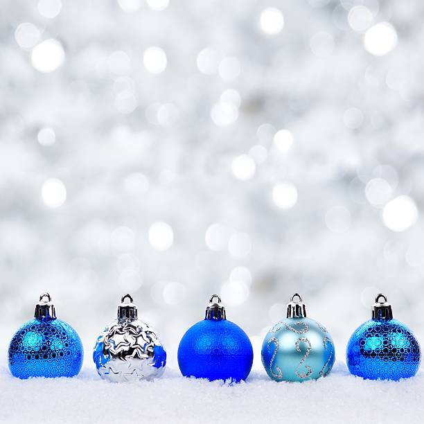 istock Blue and silver Christmas ornaments in snow with twinkling background 619979910