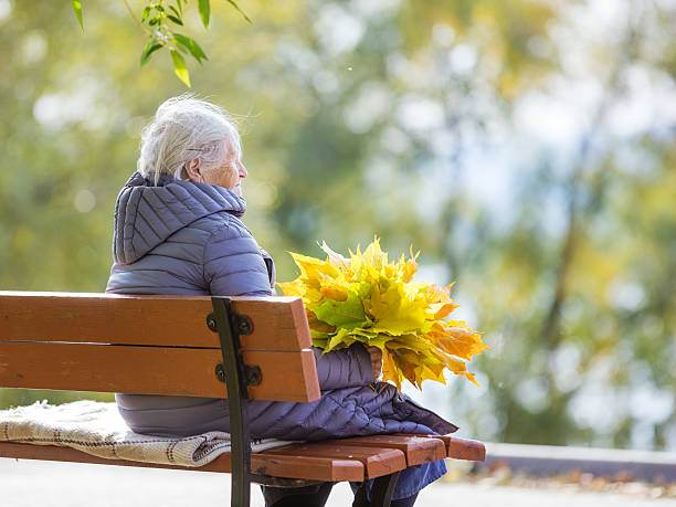 istock Senior woman sitting on bench in park 619982272