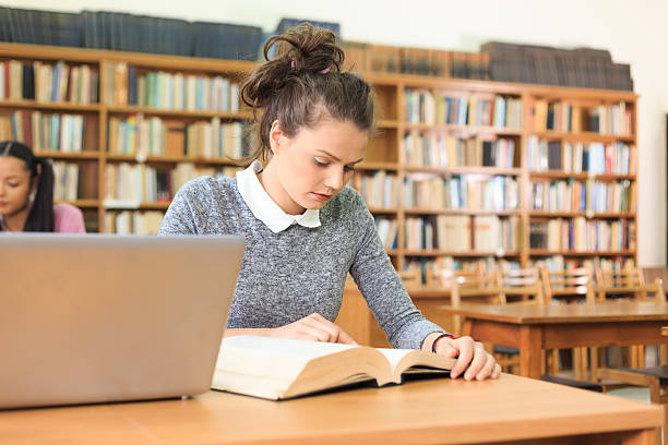 istock Girl reading a book at library 619984814