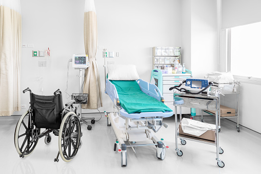 Empty wheelchair parked in hospital room with beds and comfortable medical equipped in a modern hospital