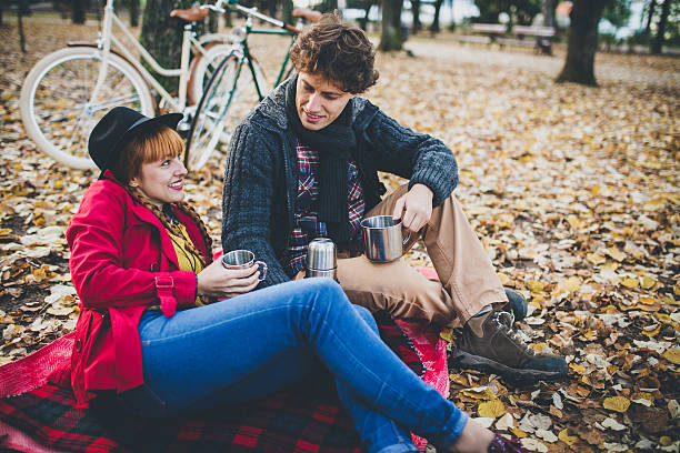 Warming up with cup of tea Couple drinking tea in park after a bicycle ride pretty redhead with her bike stock pictures, royalty-free photos & images