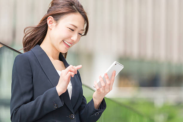 スマートフォンを持つ日本のビジネスウーマン - スマホ 日本人 ストックフォトと画像